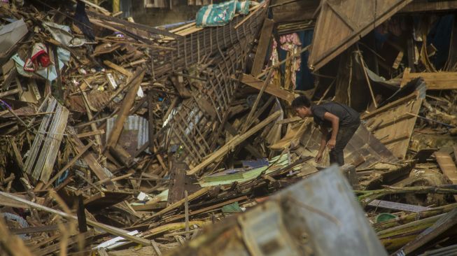 Seorang warga berada di puing-puing rumah akibat banjir bandang di Desa Waki, Kecamatan Batu Benawa,Kabupaten Hulu Sungai Tengah, Kalimantan Selatan, Rabu (20/1/2021). [ANTARA FOTO/Bayu Pratama ]