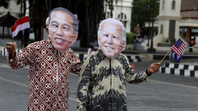 Warga menggunakan topeng berwajah presiden RI Joko Widodo (kiri) dan presiden Amerika Serikat terpilih Joe Biden (kanan) berjalan bersama saat aksi di Jalan Jendral Sudirman, Solo, Jawa Tengah, Rabu (20/1/2021).  ANTARA FOTO/Maulana Surya
