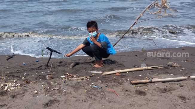 Angga Satria (8) menunjukkan lokasi penemuan tempurung kepala manusia di sekitar Pantai KSS, Pakuhaji, Kabupaten Tangerang, Rabu (20/1/2021). [Suara.com/Muhammad Jehan Nurhakim]