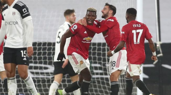 Gelandang Manchester United Paul Pogba melakukan selebrasi dengan Bruno Fernandes usai mencetak gol kedua timnya saat menghadapi Fulham dalam laga lanjutan Liga Inggris di Craven Cottage, Kamis (21/1/2021) dini hari WIB. [Clive Rose / POOL / AFP].