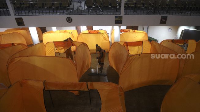 Petugas membersihkan tempat isolasi di Gedung Balai Latihan Kesenian, Jl. K.H. Mas Mansyur, Jakarta Pusat, Kamis (21/1/2021). [Suara.com/Angga Budhiyanto]