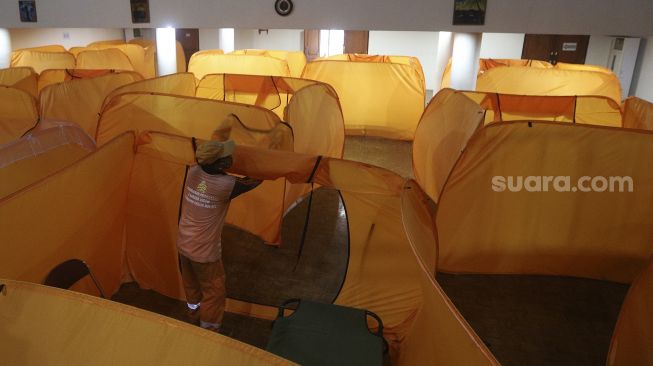 Petugas menyiapkan tempat isolasi di Gedung Balai Latihan Kesenian, Jl. K.H. Mas Mansyur, Jakarta Pusat, Kamis (21/1/2021). [Suara.com/Angga Budhiyanto]