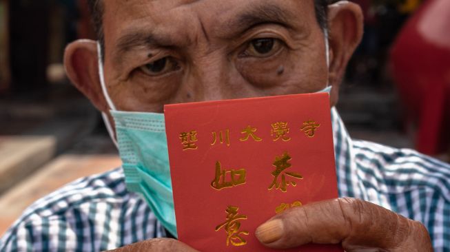 Warga lanjut usia (lansia) menunjukkan angpau yang diterimanya dari Yayasan Kelenteng Tay Kak Sie, Semarang, Jawa Tengah, Jumat (22/1/2021).  [ANTARA FOTO/Aji Styawan]