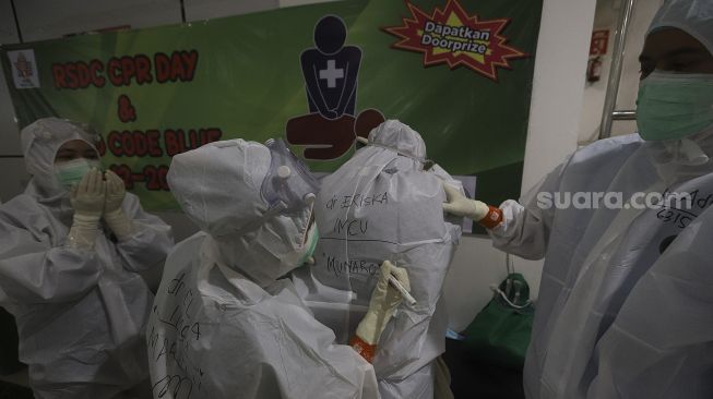 Seorang tenaga kesehatan menuliskan nama rekannya di bagian belakang baju hazmat di Rumah Sakit Darurat Penanganan COVID-19 Wisma Atlet Kemayoran, Jakarta, Jumat (22/1/2021). [Suara.com/Angga Budhiyanto]