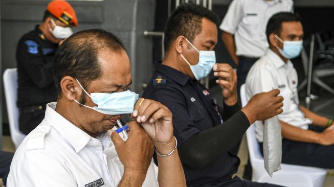 Pegawai PT KAI (persero) menghembuskan nafasnya pada kantong nafas untuk dites dengan GeNose C19 di Stasiun Pasar Senen, Jakarta, Sabtu (23/1/2021). [ANTARA FOTO/M Risyal Hidayat]