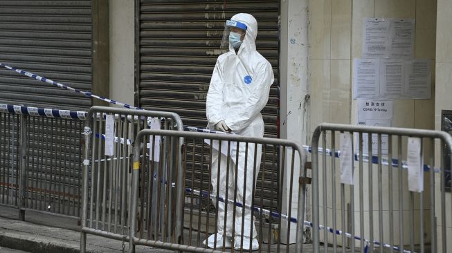 Seorang petugas kesehatan berdiri di luar sebuah gedung yang ditutup di daerah Yordania, Hong Kong, Sabtu (23/1/2021). [Peter PARKS / AFP]