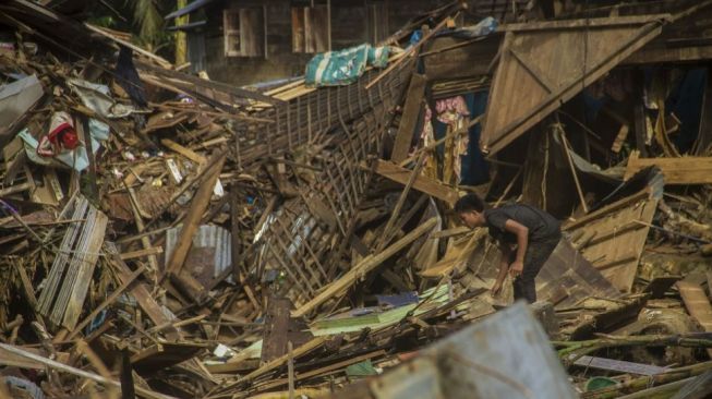 Seorang warga berada di puing-puing rumah akibat banjir bandang di Desa Waki, Kecamatan Batu Benawa,Kabupaten Hulu Sungai Tengah, Kalimantan Selatan, Rabu (20/1/2021). Berdasarkan data bencana alam banjir Badan Penanggulangan Bencana Daerah (BPBD) Kabupaten Hulu Sungai Tengah pada Selasa (18/1/2021) sebanyak 57.624 jiwa terdampak banjir serta sembilan warga dinyatakan meninggal dunia dan enam lainnya hilang. [ANTARA FOTO/Bayu Pratama ]