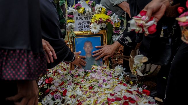 Keluarga menyentuh foto almarhum Praka (Anumerta) Roy Vebrianto, Anggota Yonif Raider 400/BR setelah melaksanakan prosesi pemakaman di Taman Makam Pahlawan, Cikutra, Bandung, Jawa Barat, Minggu (24/1/2021). .  [ANTARA FOTO/Raisan Al Farisi]