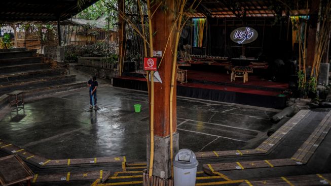 Pekerja membersihkan lantai aula pertunjukan di Saung Angklung Udjo, Bandung, Jawa Barat, Minggu (24/1/2021). [ANTARA FOTO/Raisan Al Farisi]
