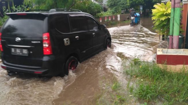 Sebuah mobil menerjang banjir di Kota Bekasi, Minggu (24/1/2021).[Dok/BPBD Kota Bekasi]