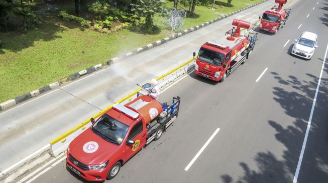 Petugas dari Badan Intelijen Negara (BIN) melakukan penyemprotan cairan disinfektan ke arah sepeda sewa yang berada di Jalan Medan Merdeka Timur, Jakarta, Senin (25/1/2021). ANTARA FOTO/M Risyal Hidayat