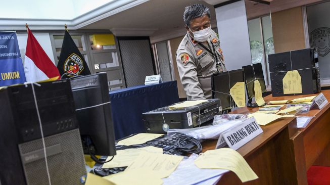 Polisi merapikan barang bukti kasus pemalsuan surat keterangan hasil tes swab saat rilis di Ditreskrimum Polda Metro Jaya, Jakarta, Senin (25/1/2021).[ANTARA FOTO/M Risyal Hidayat]