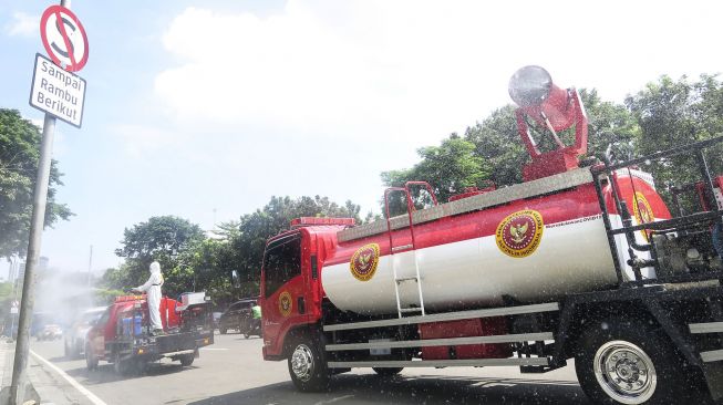 Petugas dari Badan Intelijen Negara (BIN) melakukan penyemprotan cairan disinfektan ke arah sepeda sewa yang berada di Jalan Medan Merdeka Timur, Jakarta, Senin (25/1/2021). ANTARA FOTO/M Risyal Hidayat