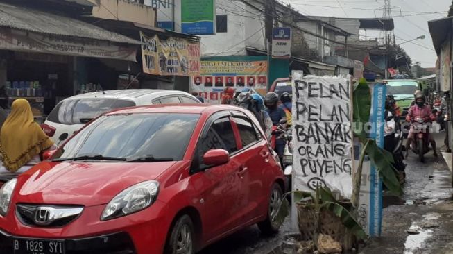 Spanduk bernada sindiran kepada terkait Jalan Raya Pabuaran yang merupakan jalan penghubung Kabupaten Bogor-Depok, Senin (25/1/2021). [SuaraBogor.id/Andi Ahmad Sulaendi]