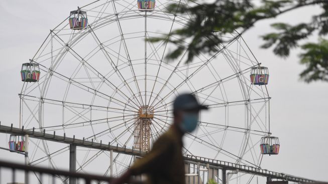 Warga berjalan di samping kawasan Suroboyo Carnival Park yang telah dibongkar di Surabaya, Jawa Timur, Senin (25/1/2021). [ANTARA FOTO/Zabur Karuru]