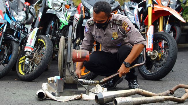 Seorang petugas kepolisian memotong knalpot balap hasil sitaan saat razia di Mapolresta Pontianak, Kalimantan Barat, Senin (25/1/2021). [ANTARA FOTO/Jessica Helena Wuysang]