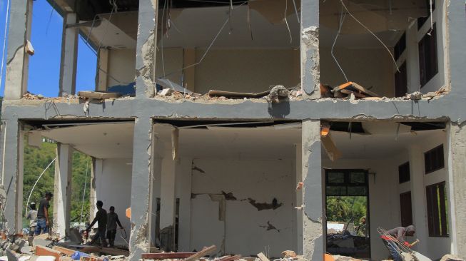 Sejumlah pekerja mencari sisa puing bangunan sekolah SMK 1 Rangas yang roboh pasca gempa bumi di Mamuju, Sulawesi Barat, Selasa (26/1/2021).  [ANTARA FOTO / Akbar Tado]