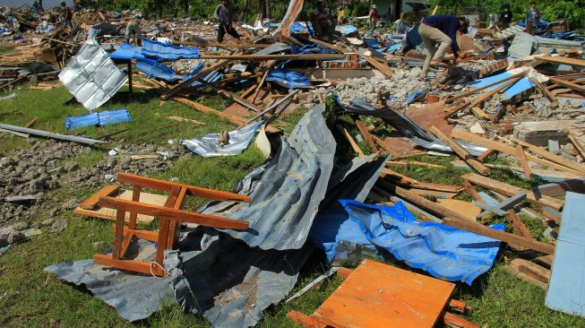 Sejumlah pekerja mencari sisa puing bangunan sekolah SMK 1 Rangas yang roboh pasca gempa bumi di Mamuju, Sulawesi Barat, Selasa (26/1/2021).  [ANTARA FOTO / Akbar Tado]