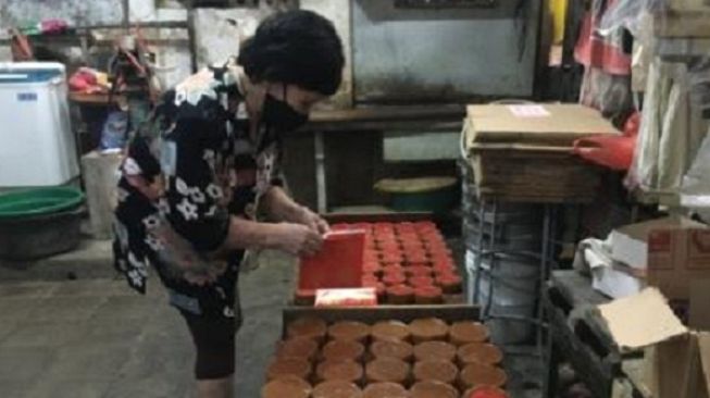  Pemilik Toko Mini Bakery, Ratna Anggraini, menempelkan stiker merek kue keranjang produknya, Senin (25/1/2021). (Solopos.com/Farida Trisnaningtyas)