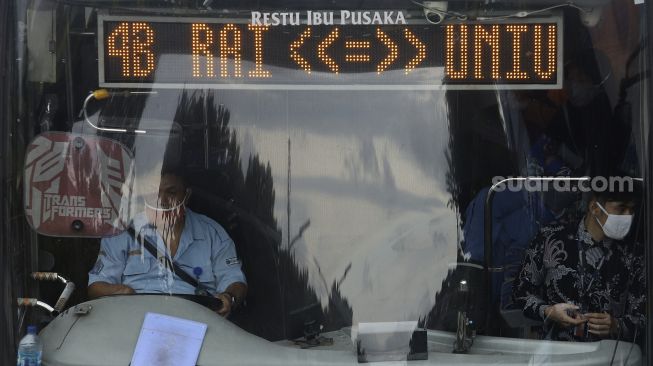 Supir bus Transjakarta mengenakan masker saat melintas di kawasan Pasar Minggu, Jakarta, Selasa (26/1/2021). [Suara.com/Angga Budhiyanto]