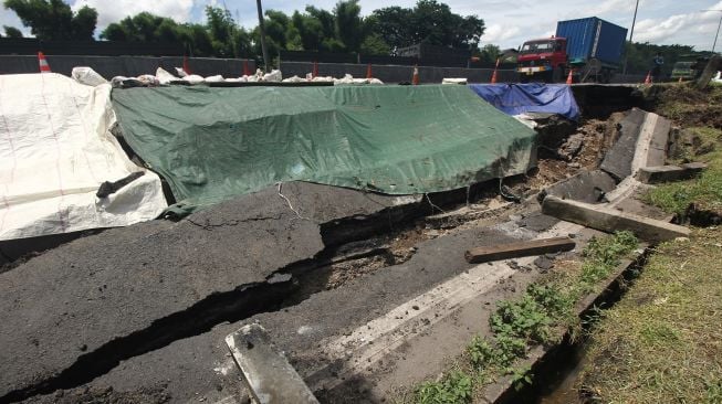 Sejumlah kendaraan melintas di dekat jalan tol yang longsor di ruas tol Surabaya-Gempol KM 06+200, di Surabaya, Jawa Timur, Rabu (27/1/2021).  [ANTARA FOTO/Didik Suhartono]
