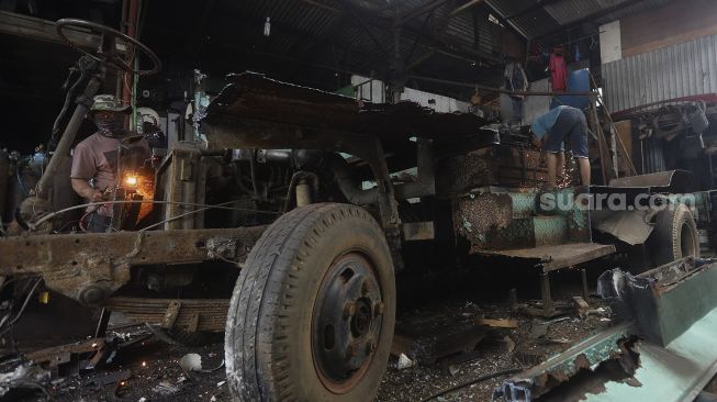 Pekerja membongkar bus Kopaja yang akan diremajakan di kawasan Meruya, Jakarta Barat, Rabu (27/1/2021). [Suara.com/Angga Budhiyanto]