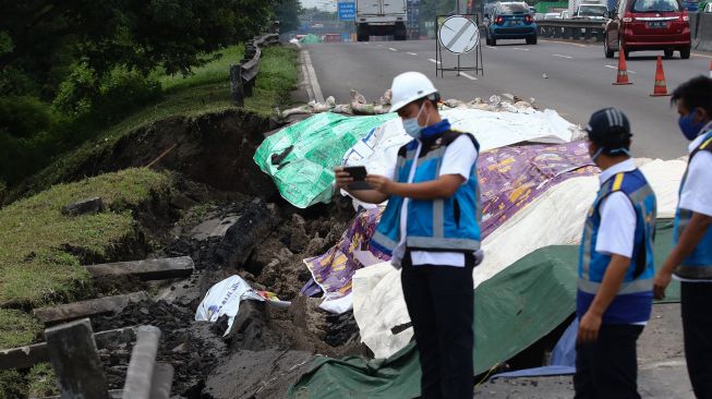 Petugas memeriksa jalan tol yang longsor di ruas tol Surabaya-Gempol KM 06+200, di Surabaya, Jawa Timur, Rabu (27/1/2021). [ANTARA FOTO/Didik Suhartono]