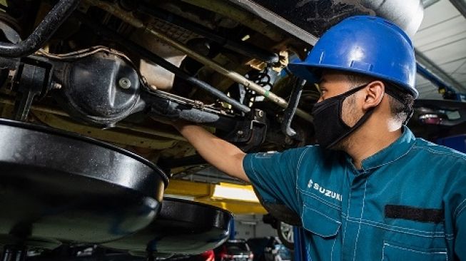 Seorang mekanik tengah mengecek kondisi pelumas sebuah mobil di bengkel resmi Suzuki [Dok PT SIS].