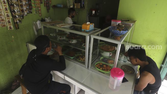 Pembeli menyantap makanan di Warteg Dias Berkah, Jati Padang, Pasar Minggu, Jakarta, Rabu (27/1/2021). [Suara.com/Angga Budhiyanto]