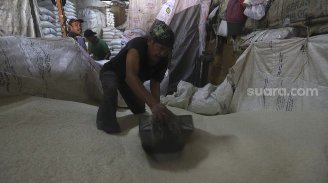 Pekerja mengemas beras ke dalam karung di Pasar Induk Beras Cipinang, Jakarta, Kamis(28/1/2021). [Suara.com/Angga Budhiyanto]