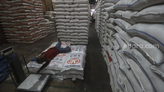 Pekerja beristirahat di sela-sela mengangkut beras di Pasar Induk Beras Cipinang, Jakarta, Kamis (28/1/2021). [Suara.com/Angga Budhiyanto]