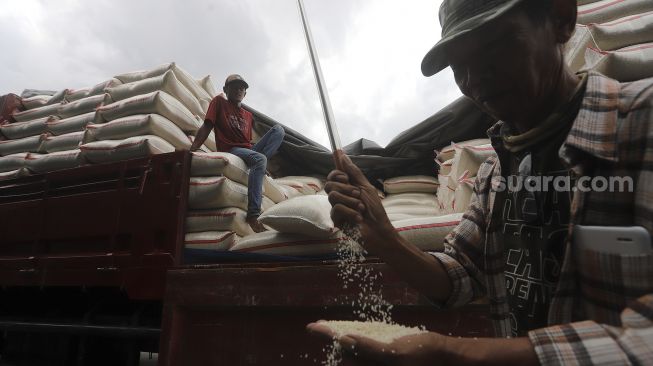 Pekerja mengecek kualitas beras di Pasar Induk Beras Cipinang, Jakarta, Kamis(28/1/2021). [Suara.com/Angga Budhiyanto]