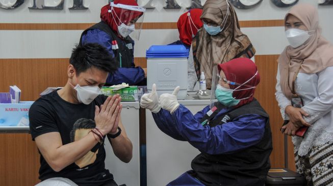 Tenaga kesehatan berbincang dengan influencer dan musisi asal Bandung, Nazril Ilham setelah menyuntikkan vaksin COVID-19 di RSKIA Kota Bandung, Jawa Barat, Kamis (28/1/2021).  [ANTARA FOTO/Raisan Al Farisi]
