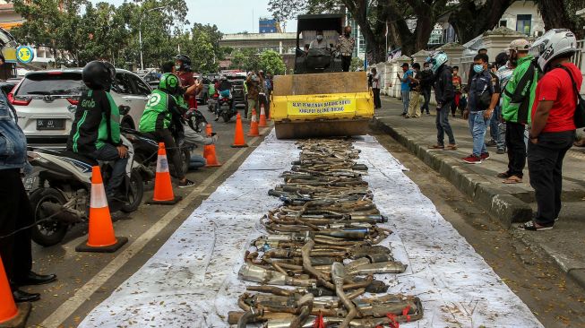 Petugas Kepolisian Satlantas Polrestabes Medan menggunakan alat berat disaat memusnahkan barang bukti tangkapan knalpot brong (bising) di Medan, Sumatera Utara, Kamis (28/1/2021). ANTARA FOTO/Rony Muharrma