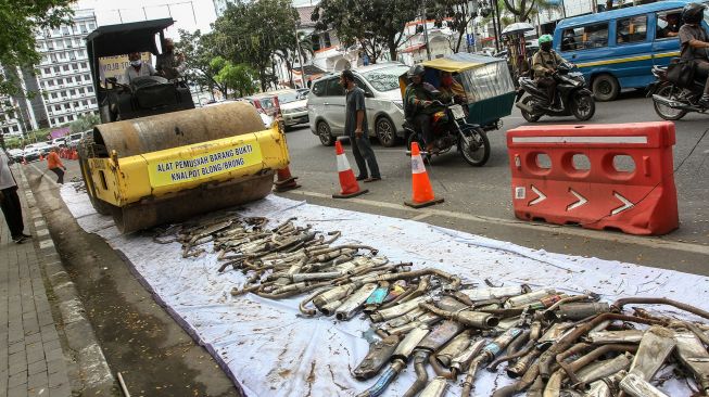 Petugas Kepolisian Satlantas Polrestabes Medan menggunakan alat berat disaat memusnahkan barang bukti tangkapan knalpot brong (bising) di Medan, Sumatera Utara, Kamis (28/1/2021). ANTARA FOTO/Rony Muharrma