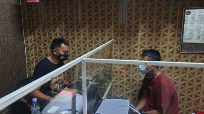 Nurman Gustianto (24) menjalani pemeriksaan oleh polisi. Dia merupakan pelaku pembakaran minimarket tempatnya bekerja, Rabu (27/1/2021). [Foto: Bantennews.co.id]