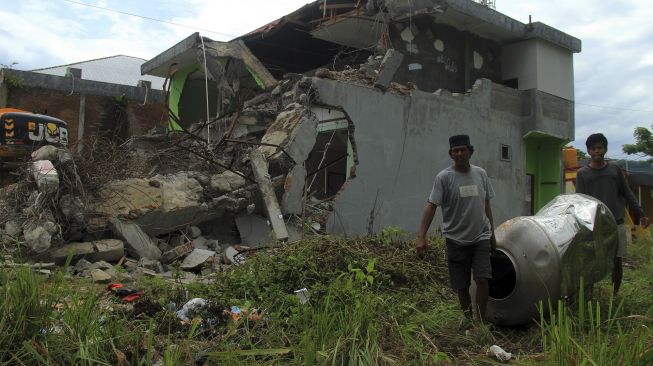 Warga mengambil barang dari sisa reruntuhan bangunan di Mamuju, Sulawesi Barat, Jumat (29/1/2021). [ANTARA FOTO / Akbar Tado]