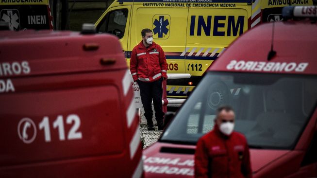 Petugas pemadam kebakaran berdiri di tengah lusinan ambulans yang menunggu di luar layanan darurat COVID-19 di Rumah Sakit Santa Maria, Lisbon, pada (28/1/2021). [PATRICIA DE MELO MOREIRA / AFP]