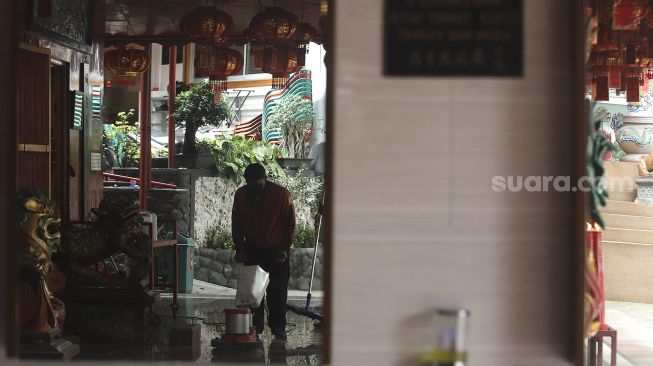 Refleksi pekerja membersihkan area Vihara Amurva Bhumi (Hok Tek Tjeng Sin) menjelang Tahun Baru China atau Imlek di Kelurahan Karet Semanggi, Jakarta, Sabtu (30/1/2021). [Suara.com/Angga Budhiyanto]