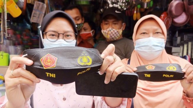 Warga memperlihatkan masker pemberian dari petugas TNI-Polri di Pasar Jatinegara, Jakarta Timur, Minggu (31/1/2021). [ANTARA/Andi Firdaus]