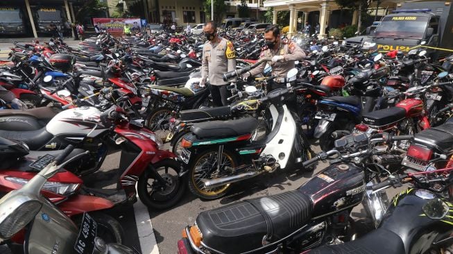 Polisi mengamati barang bukti sepeda motor hasil penindakan balap liar di Polres Kediri, Jawa Timur, Senin (1/2/2021). ANTARA FOTO/Prasetia Fauzani