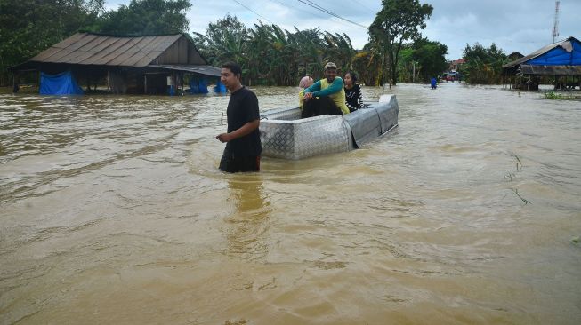 Warga menggunakan perahu melintasi jalan yang terendam banjir di Desa Kedungdowo, Kudus, Jawa Tengah, Selasa (2/2/2021). [ANTARA FOTO/Yusuf Nugroho]
