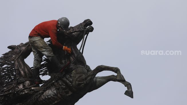 Pekerja melakukan perawatan patung Asta Brata (Arjuna Wijaya) di jalan Medan Merdeka Barat, Jakarta, Selasa (2/2/2021). [Suara.com/Angga Budhiyanto]