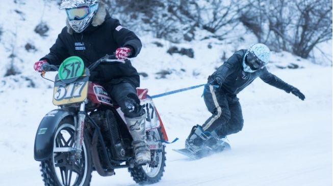 Salah satu opsi bermain motor di atas danau beku: balap menyeret teman bermain snowboarding [YouTube, Visordown].