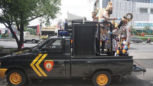 Anggota Polisi dengan mengenakan kostum wayang menaiki mobil saat kegiatan sosialisasi dan pembagian masker, di Pasar Ngudi Rejeki, Gilingan, Solo, Jawa Tengah, Rabu (3/2/2021). ANTARA FOTO/Mohammad Ayudha