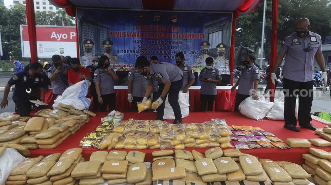 Petugas kepolisian memasukkan kembali barang bukti narkotika usai diperlihatkan saat pemusnahan hasil pengungkapan kasus narkotika di Mapolda Metro Jaya, Jakarta, Rabu (3/2/2021). [Suara.com/Angga Budhiyanto]