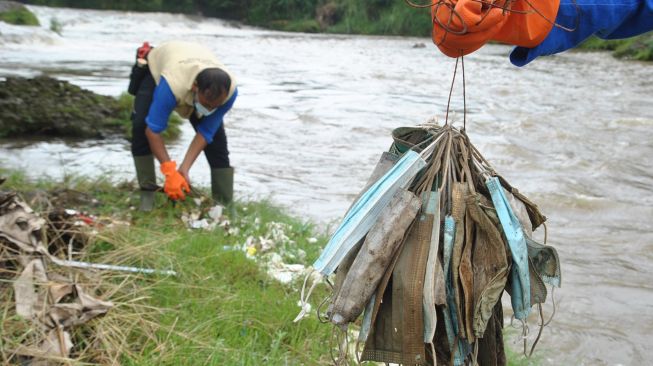 Anggota satgas naturalisasi Ciliwung Kota Bogor mengumpulkan sampah masker medis bekas pakai, di bantaran sungai Ciliwung, Kelurahan Sukaresmi, Kota Bogor, Jawa Barat, Rabu (3/2/2021). ANTARA FOTO/Arif Firmansyah