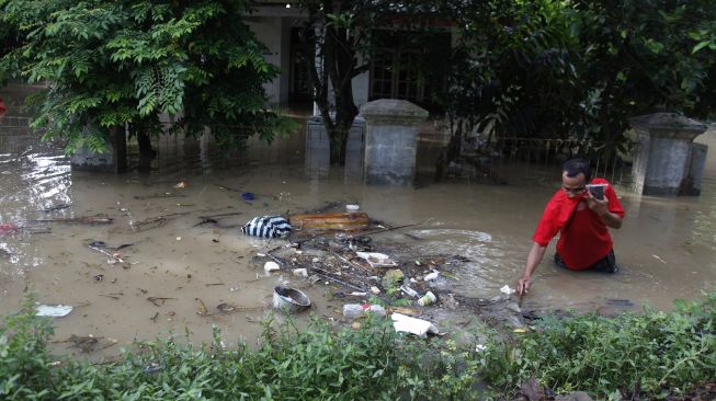 Warga melintasi banjir yang menggenangi permukiman di Kampung Sewu, Jebres, Solo Jawa Tengah, Kamis (4/2/2021). [ANTARA FOTO/Maulana Surya]
