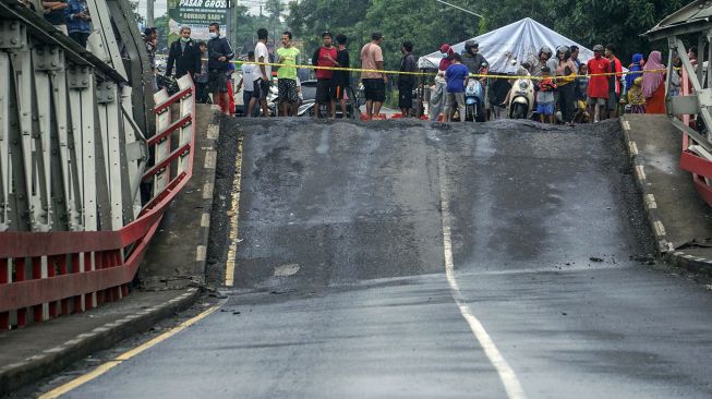 Warga melihat jembatan perbatasan yang ambles di Kabupaten Pekalongan, Jawa Tengah, Jumat (5/2/2021). ANTARA FOTO/Harviyan Perdana Putra
