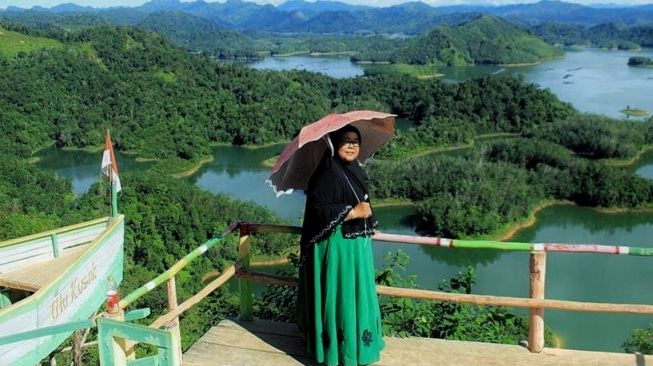 Pengunjung saat menikmati pemandangan dan terik matahari dari atas bukit Ulu Kasok yang menawan.[Suara.com/Panji Ahmad Syuhada]